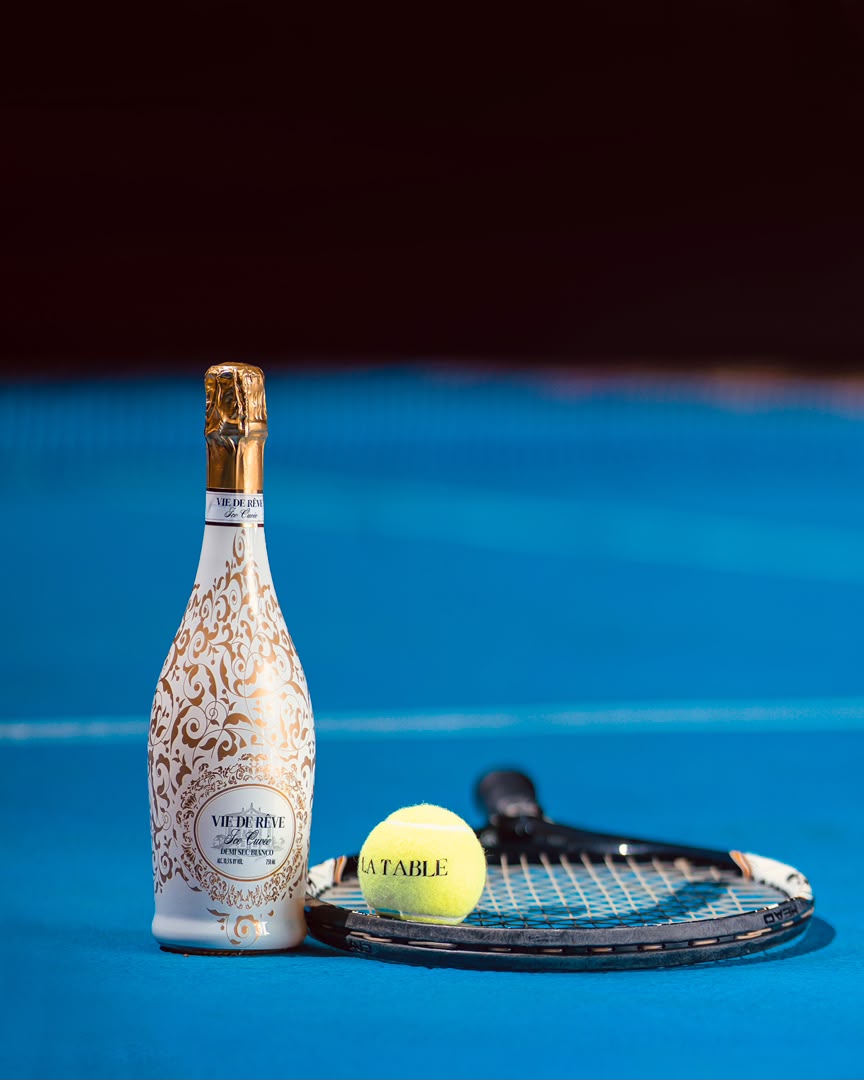 Champagne and a LA TABLE tennis ball on the court